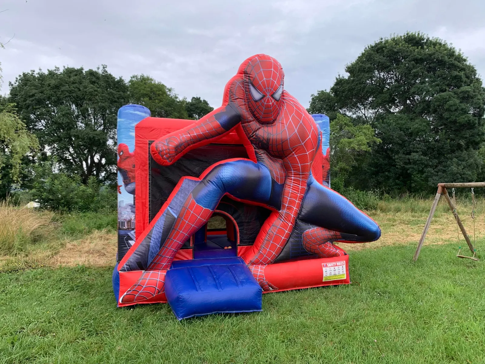 Château gonflable Spiderman installé sur une pelouse